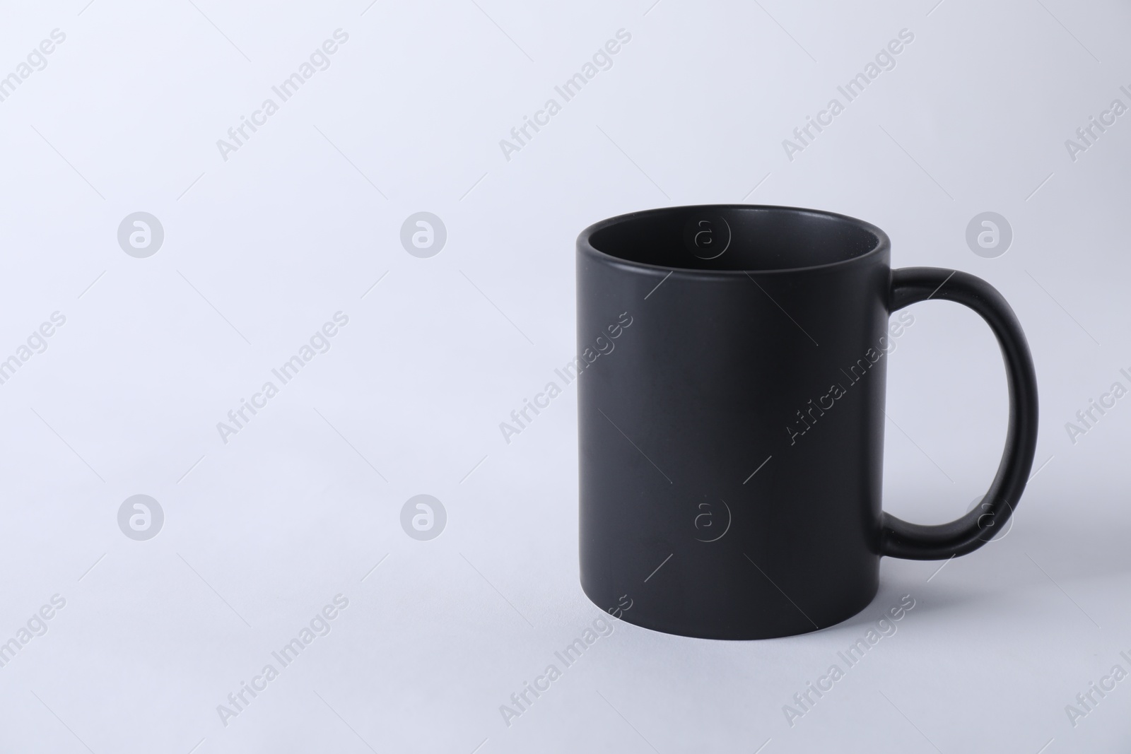 Photo of One blank black mug on white background. Mockup for design