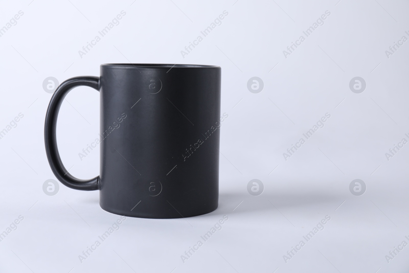 Photo of One blank black mug on white background. Mockup for design