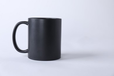 Photo of One blank black mug on white background. Mockup for design