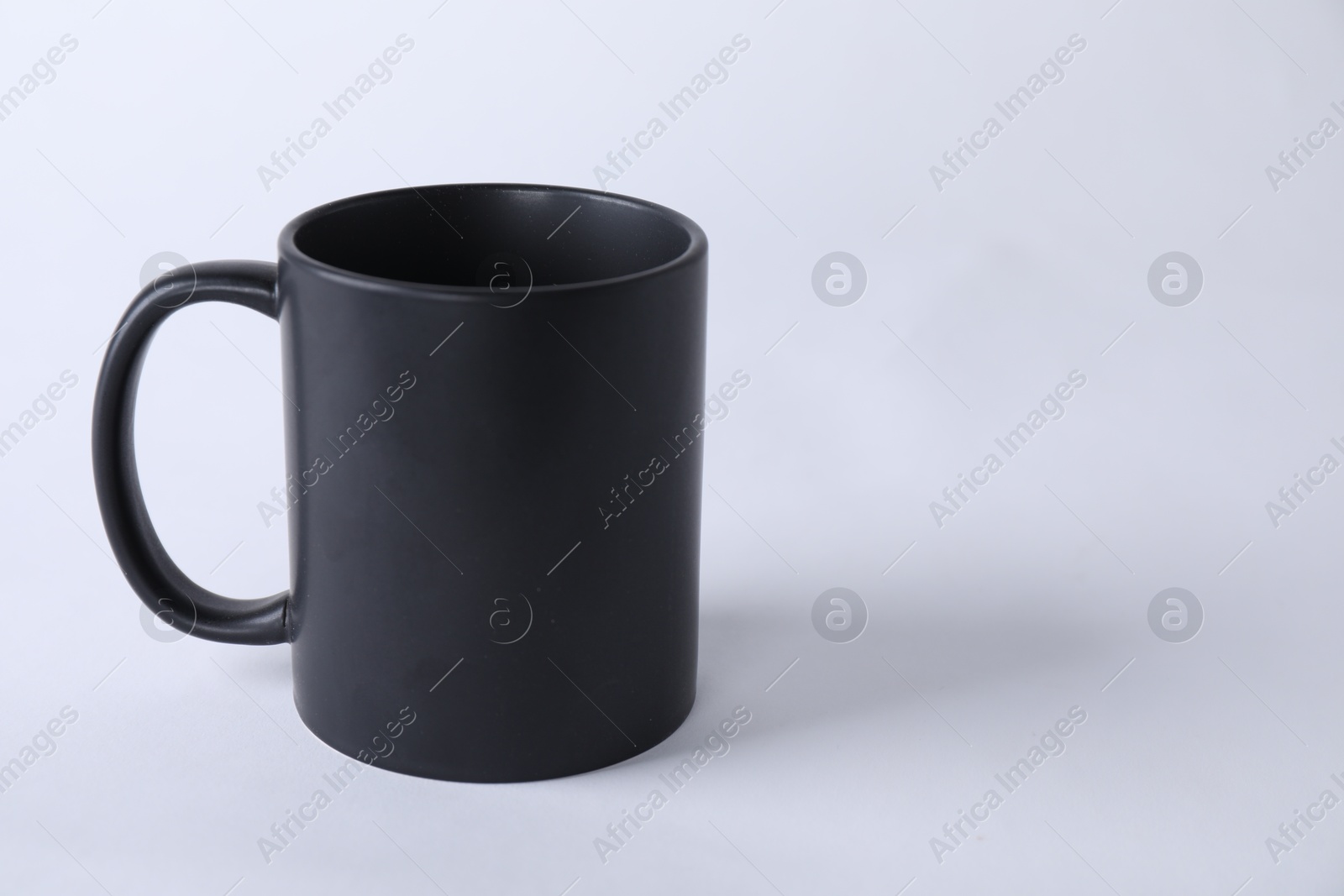 Photo of One blank black mug on white background. Mockup for design