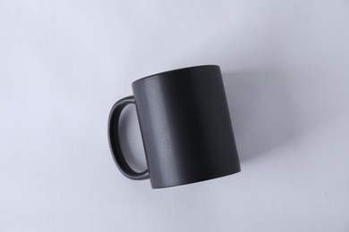 Photo of One blank black mug on white background, top view. Mockup for design