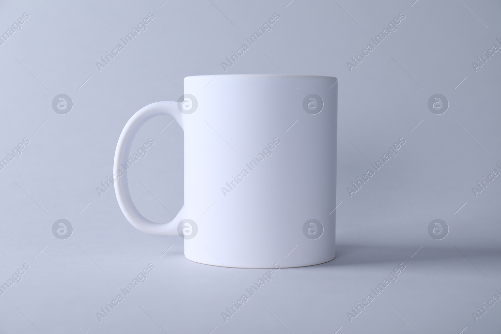 Photo of One blank white mug on light background. Mockup for design