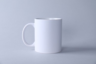 Photo of One blank white mug on light background. Mockup for design