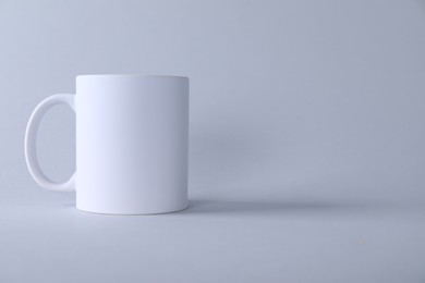 Photo of One blank white mug on light background. Mockup for design