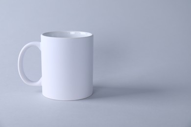 One blank white mug on light background. Mockup for design