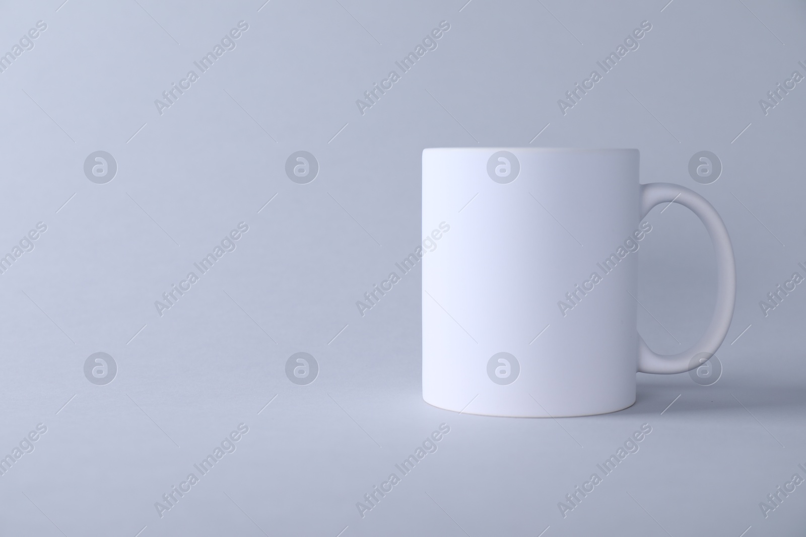 Photo of One blank white mug on light background. Mockup for design