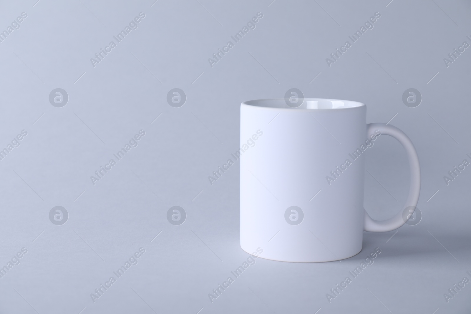 Photo of One blank white mug on light background. Mockup for design