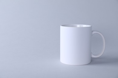 Photo of One blank white mug on light background. Mockup for design