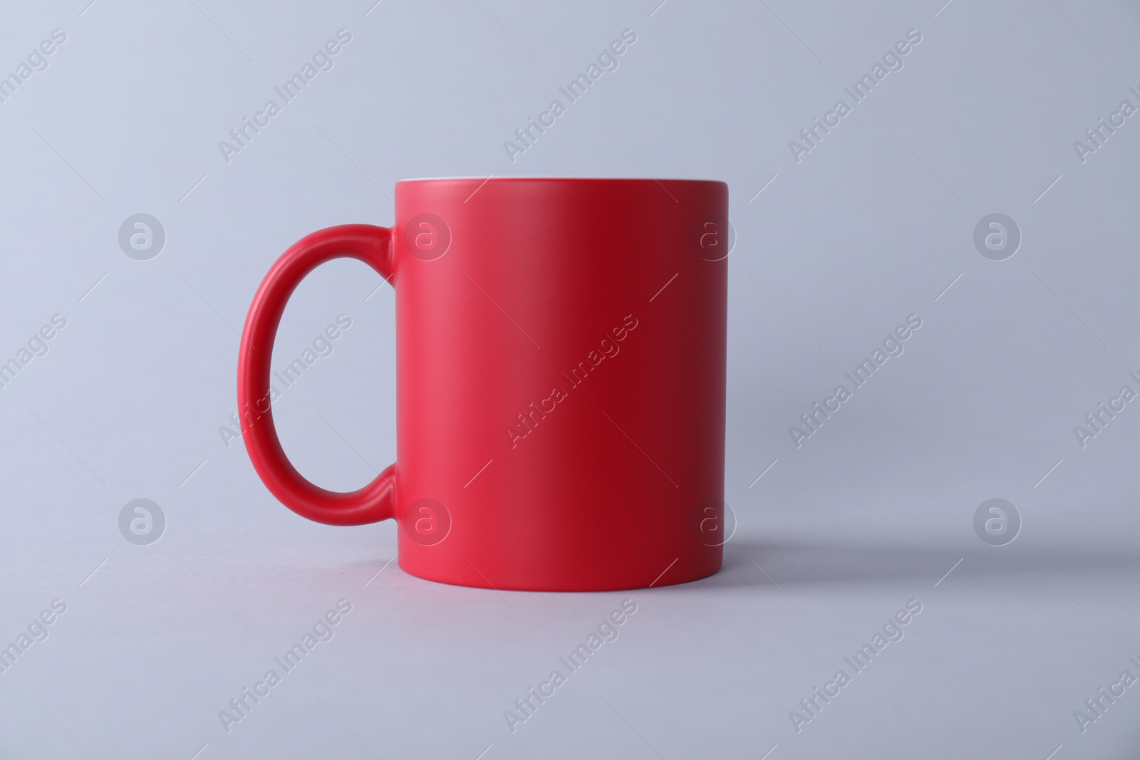 Photo of One blank red mug on light background. Mockup for design