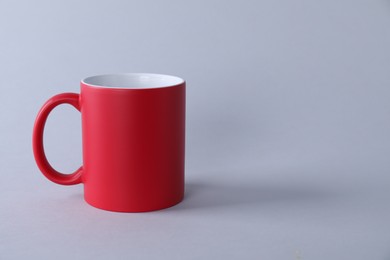 Photo of One blank red mug on light background. Mockup for design