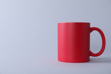 Photo of One blank red mug on light background. Mockup for design