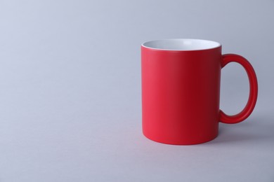 Photo of One blank red mug on light background. Mockup for design