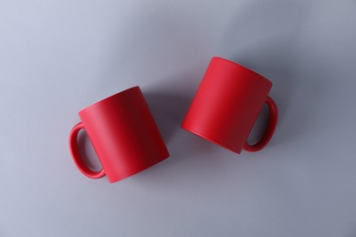 Photo of Two blank red mugs on light background, top view. Mockup for design