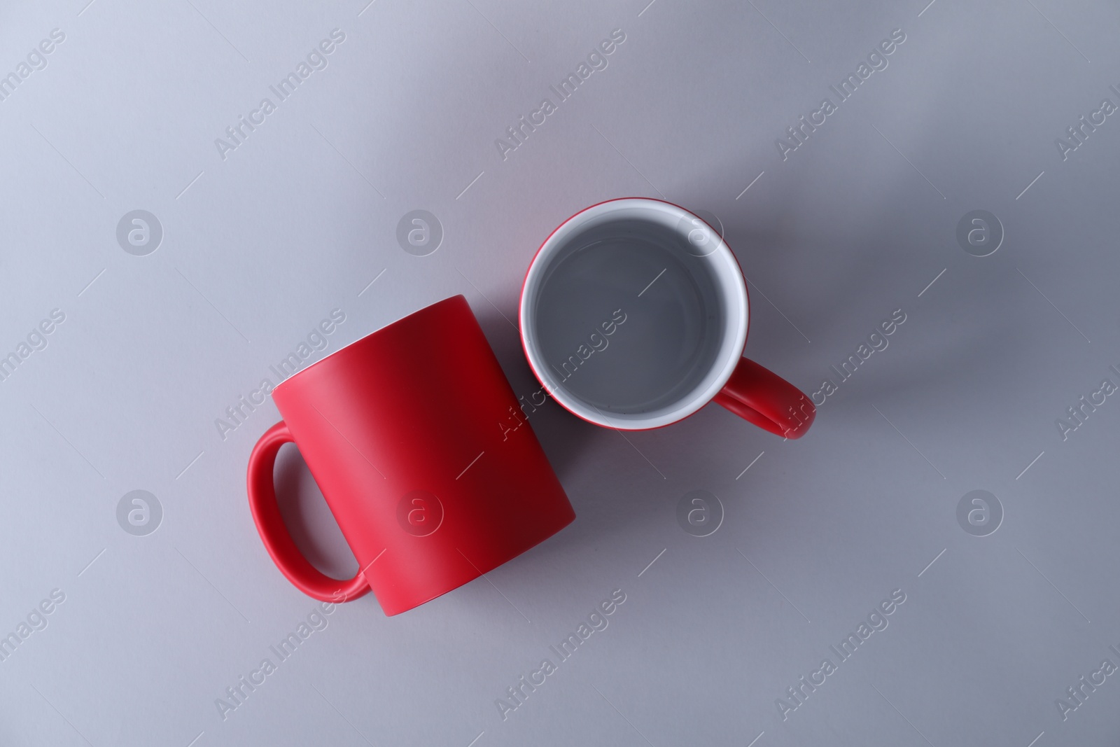 Photo of Two blank red mugs on light background, top view. Mockup for design