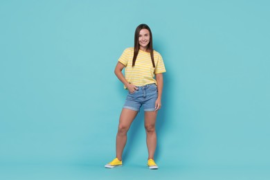 Beautiful woman wearing stylish denim shorts on light blue background