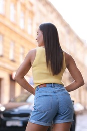 Photo of Woman wearing stylish denim shorts outdoors, back view