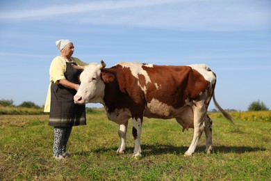 Senior woman with beautiful cow on pasture