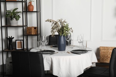 Photo of Stylish table setting with beautiful dishware and black chairs in dining room