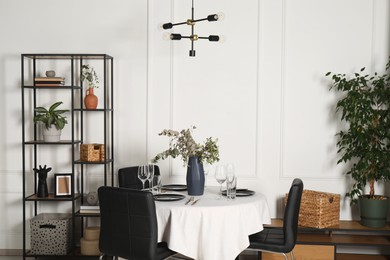 Photo of Stylish table setting with beautiful dishware and black chairs in dining room