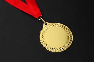 Photo of Golden medal with red ribbon on black background, closeup