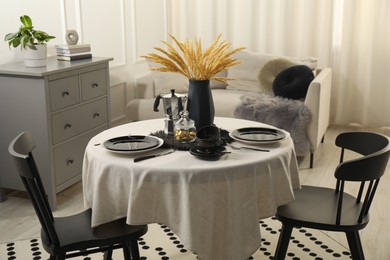 Photo of Stylish table setting with beautiful dishware and black chairs in dining room