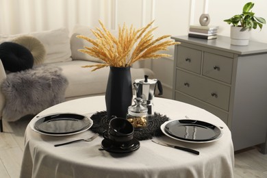 Photo of Stylish table setting with black dishware in dining room