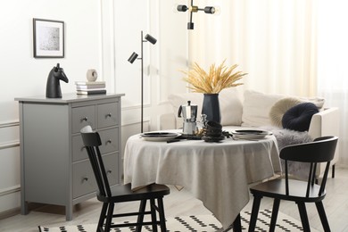 Photo of Stylish table setting with beautiful dishware and black chairs in dining room