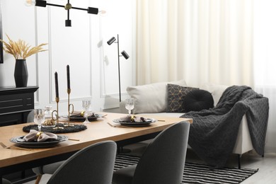 Photo of Stylish table setting with black dishware in dining room