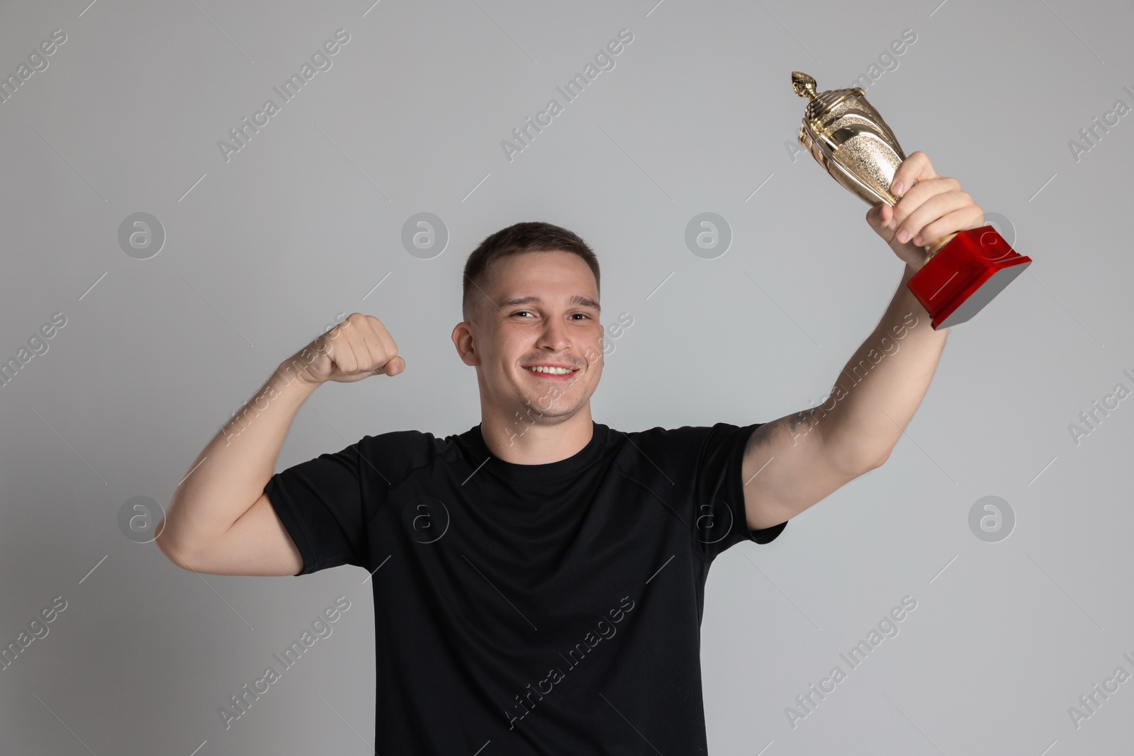 Photo of Happy winner with golden trophy cup on light grey background