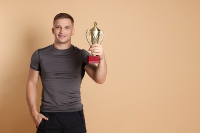 Photo of Happy winner with golden trophy cup on beige background, space for text