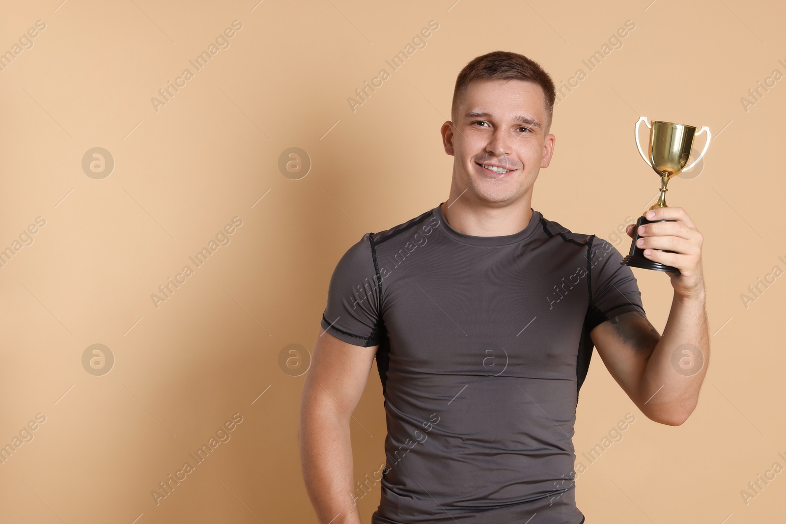 Photo of Happy winner with golden trophy cup on beige background, space for text