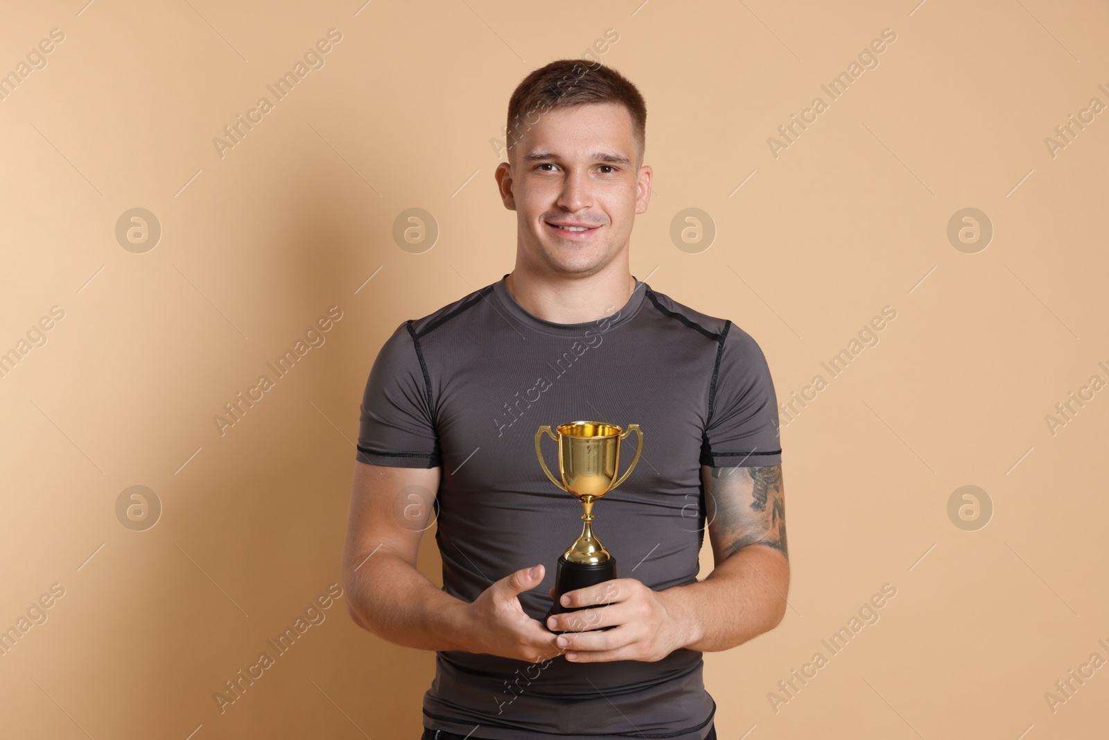 Photo of Happy winner with golden trophy cup on beige background