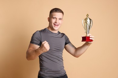 Photo of Happy winner with golden trophy cup on beige background