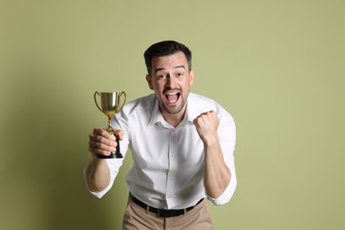 Happy winner with golden trophy cup on pale olive background