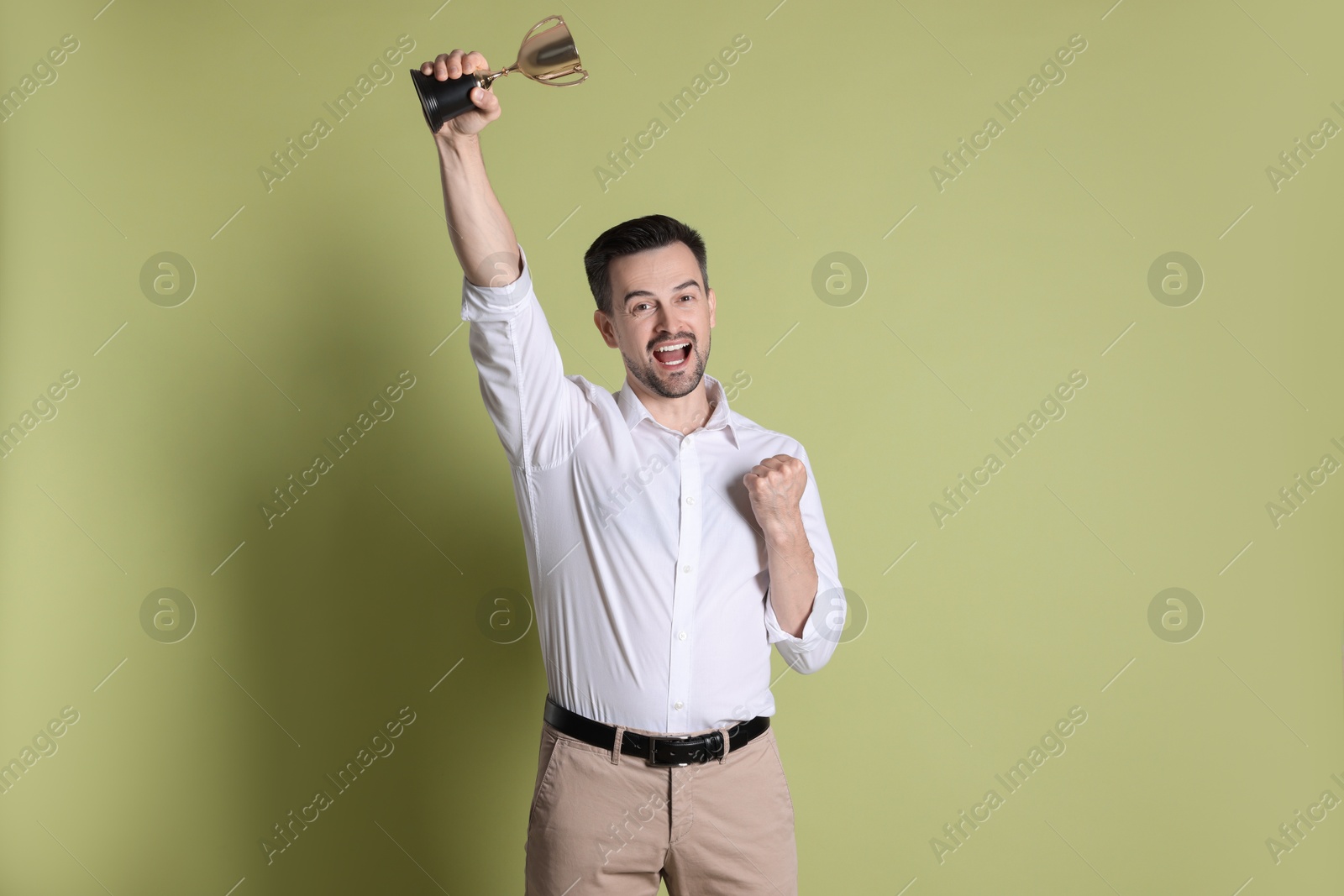 Photo of Happy winner with golden trophy cup on pale olive background