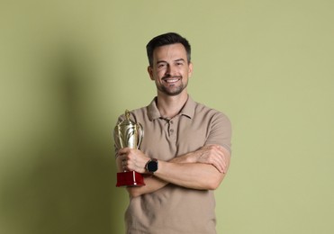 Happy winner with golden trophy cup on pale olive background