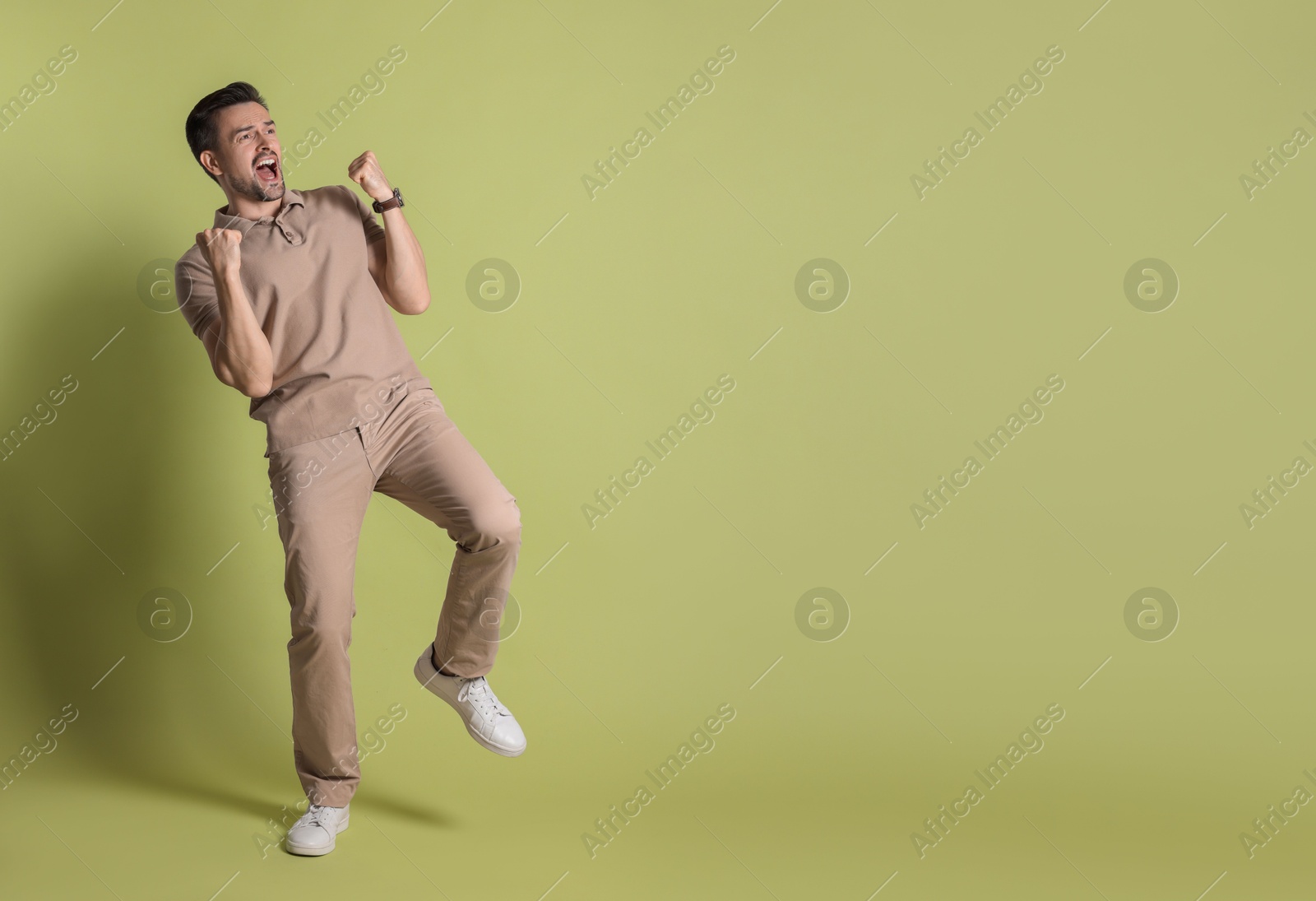 Photo of Portrait of happy winner on pale olive background