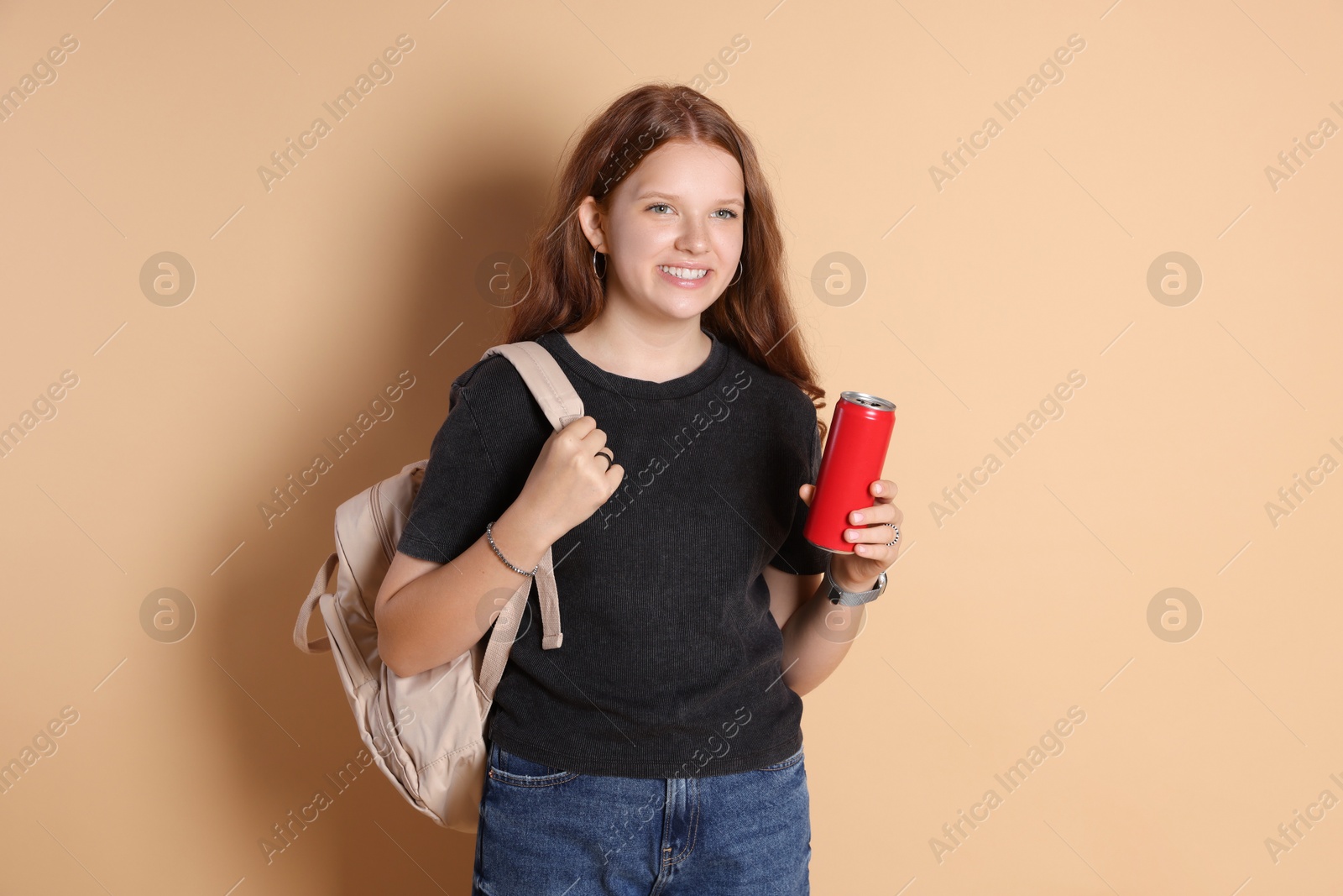 Photo of Smiling teenage girl with backpack and can on beige background