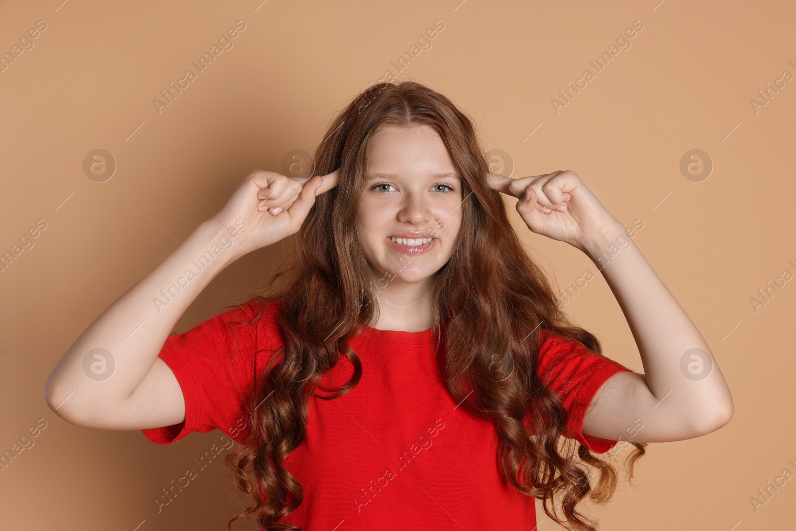 Photo of Smiling teenage girl gesturing on beige background