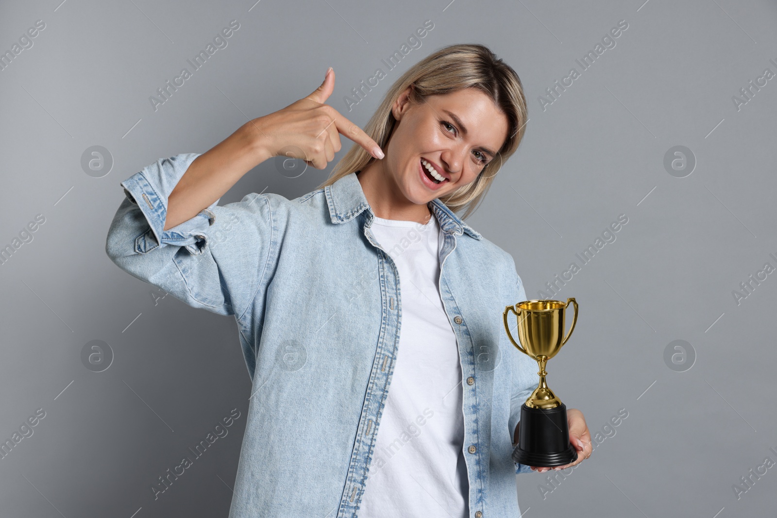 Photo of Happy winner with golden trophy cup on gray background