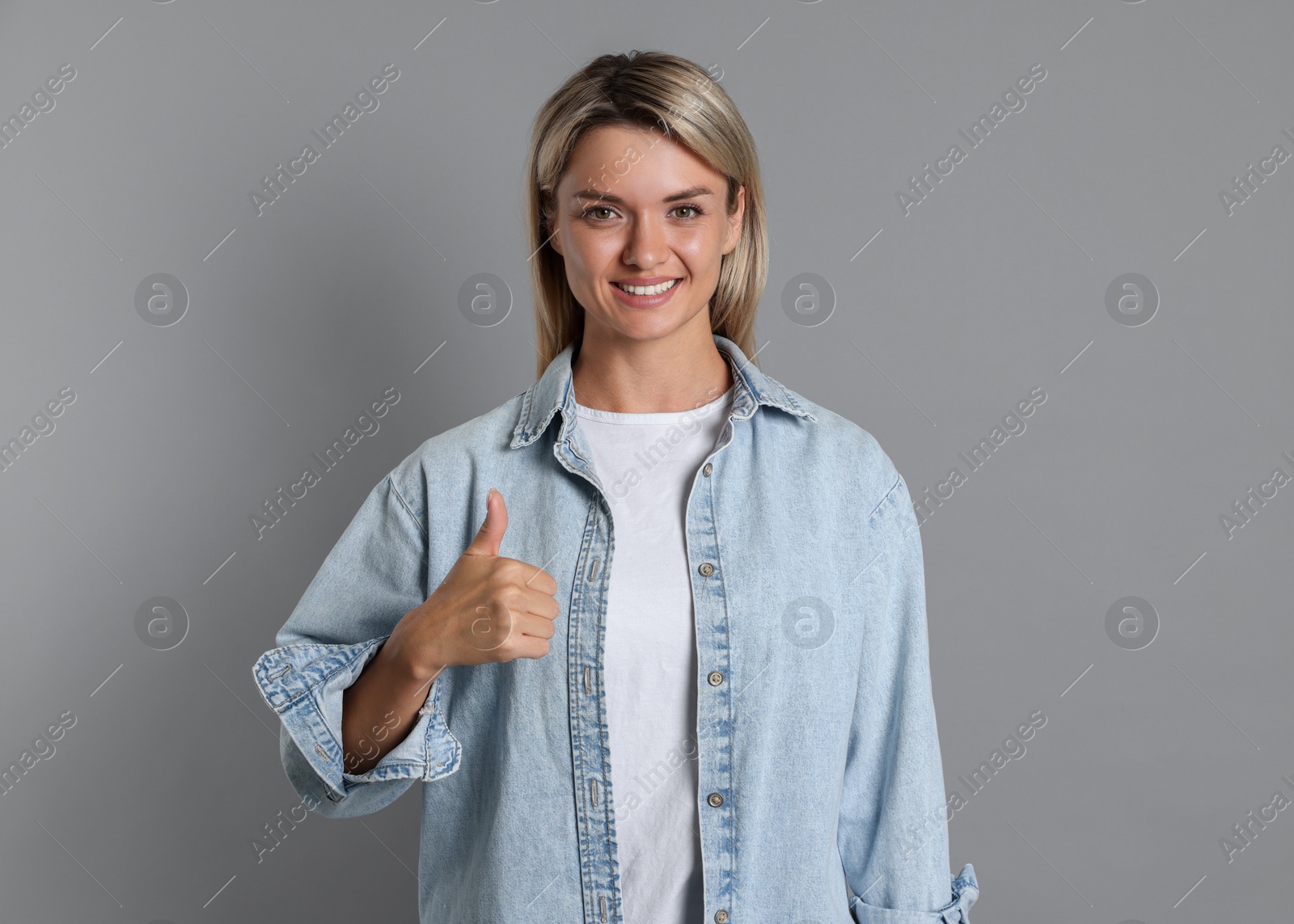 Photo of Happy winner showing thumbs up on gray background