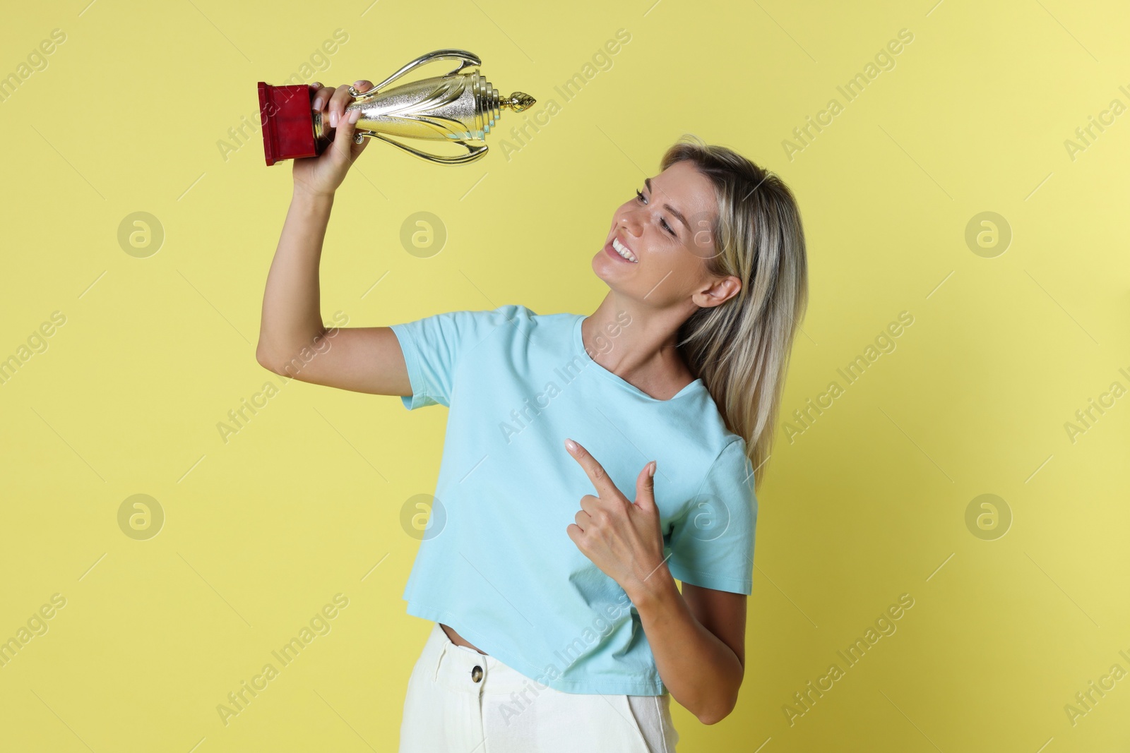 Photo of Happy winner with golden trophy cup on yellow background