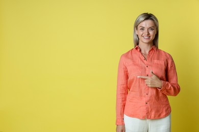 Photo of Happy winner pointing at something on yellow background, space for text