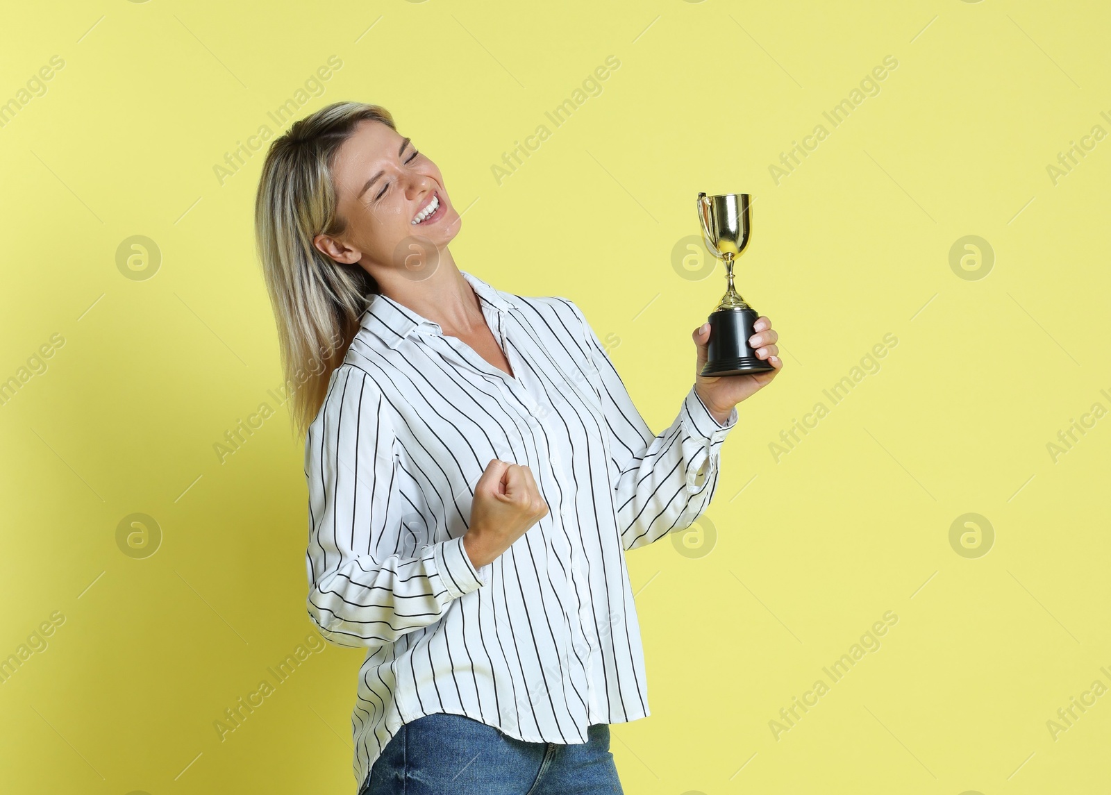 Photo of Happy winner with golden trophy cup on yellow background