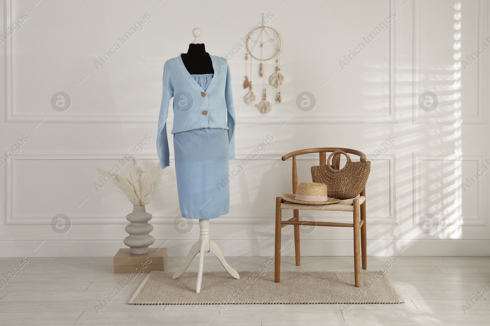 Photo of Female mannequin with clothes, chair and vase near light wall