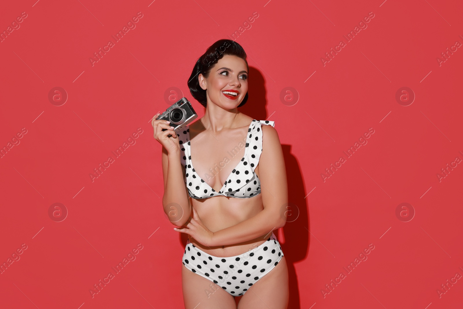 Photo of Pin-up woman in bikini with camera on red background