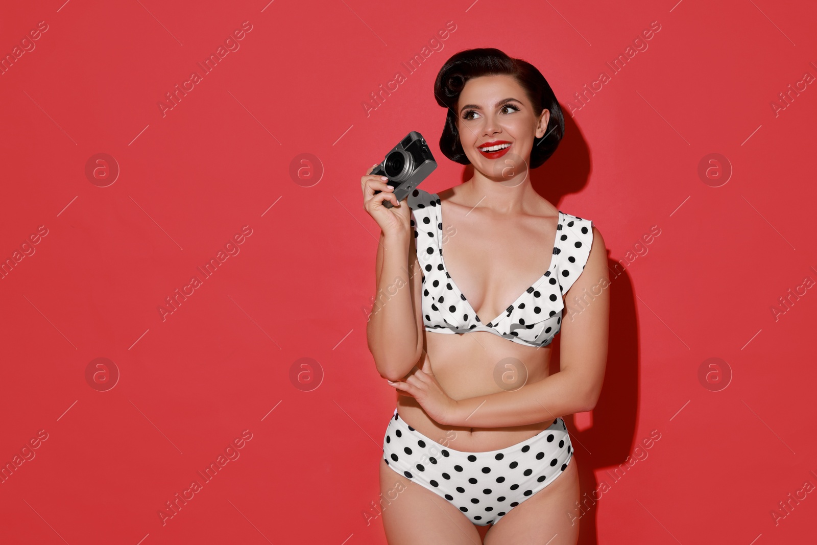 Photo of Pin-up woman in bikini with camera on red background, space for text