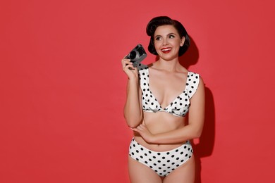 Photo of Pin-up woman in bikini with camera on red background, space for text