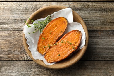 Halves of tasty cooked sweet potato with thyme on wooden table, top view