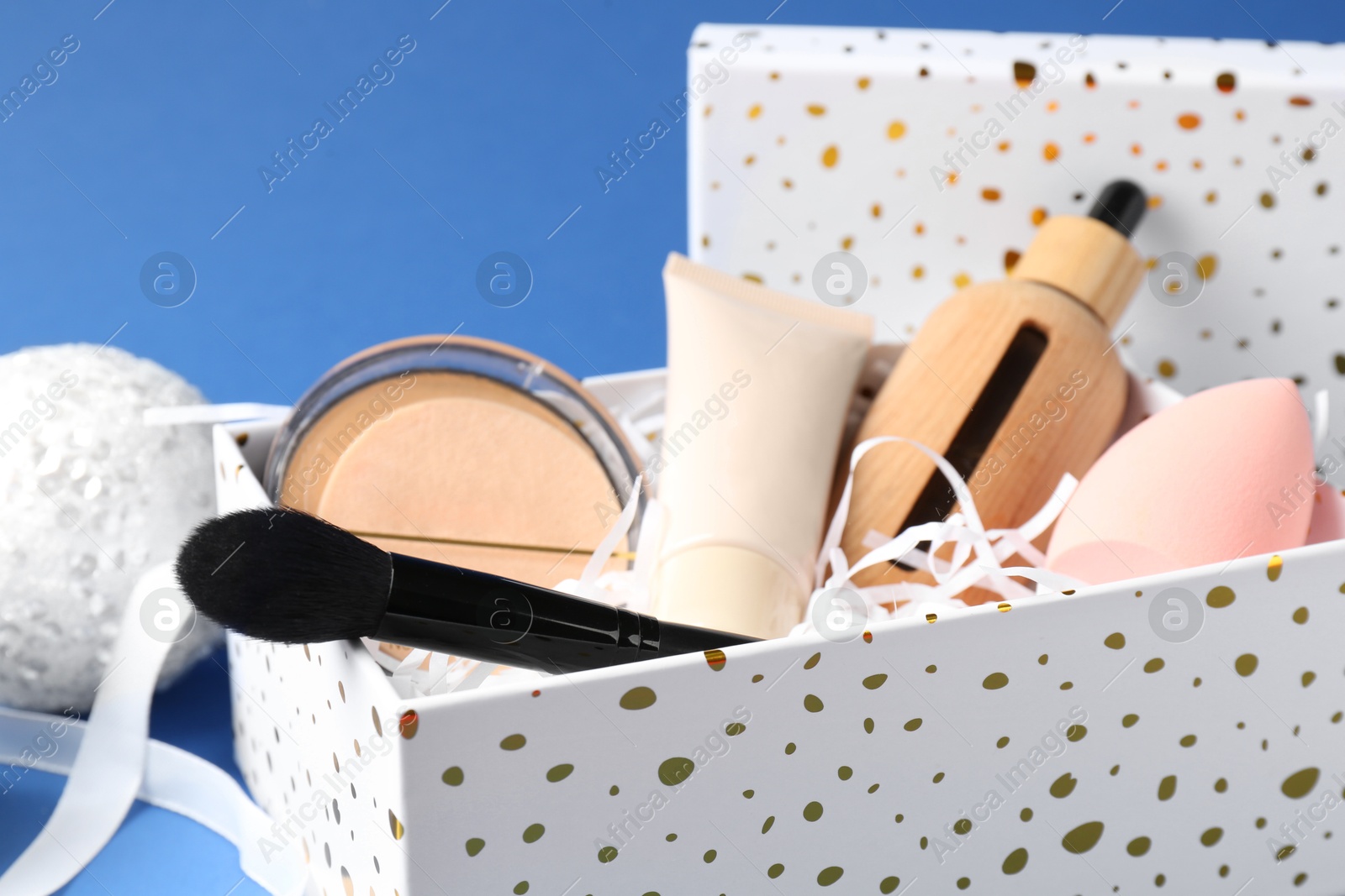 Photo of Cosmetic products in gift box on blue background, closeup. Space for text